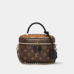 Vanity PM handbag in reverse monogram canvas with black leather trim, front view.