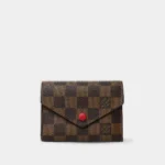 Victorine wallet in damier ebene coated canvas with red snap closure, front view.